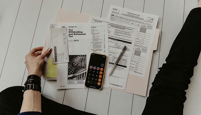 Woman reviewing tax forms and bills, using a calculator and pen to manage finances and plan purchases responsibly