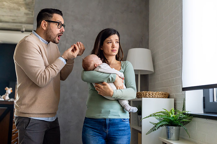 Man arguing with post-partum wife holding baby, depicting conflict over divorce and custody issues. Man arguing with post-partum wife holding baby, depicting conflict over divorce and custody issues.