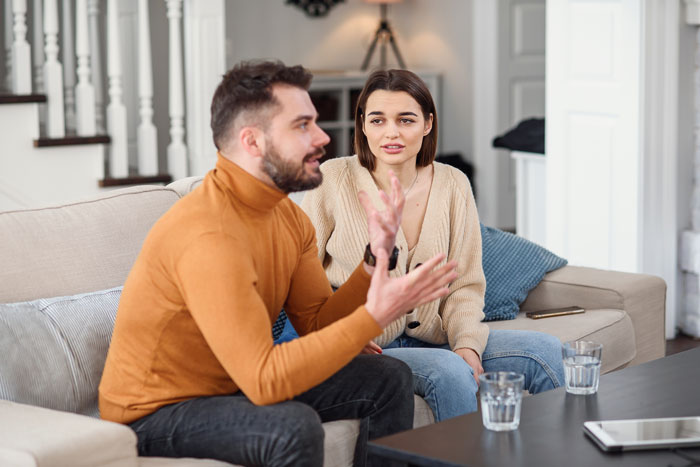 Couple having a serious conversation on a couch as woman tells fianc&eacute; his gaming days are over.