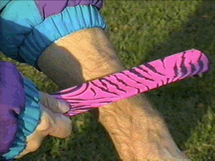 Person wearing a colorful nineties fashion slap bracelet on their wrist outdoors on grass background.