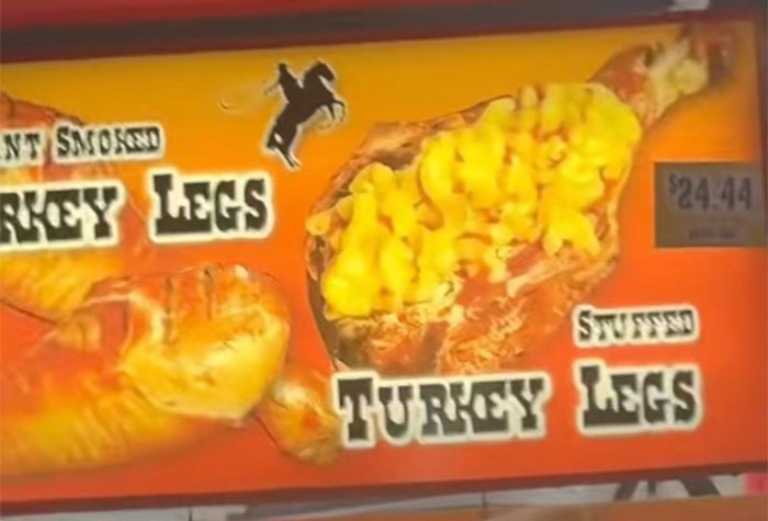 Stuffed turkey legs with macaroni and cheese displayed on a bright county fair foods menu sign.