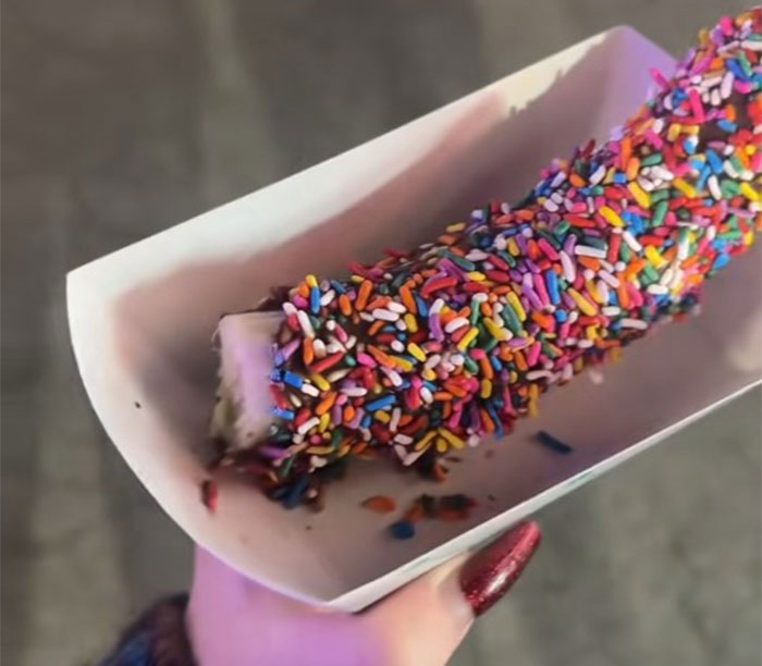 County fair food covered in colorful sprinkles held in a paper tray, showcasing indulgent and unique fair treats.