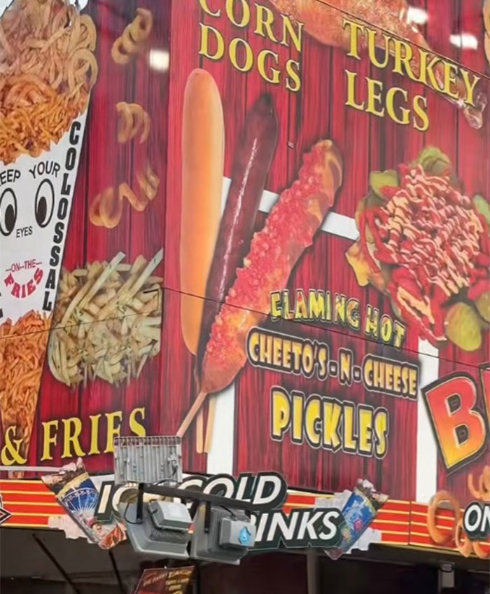 County fair foods menu board featuring corn dogs, flaming hot Cheetos-n-cheese pickles, turkey legs, and fries.