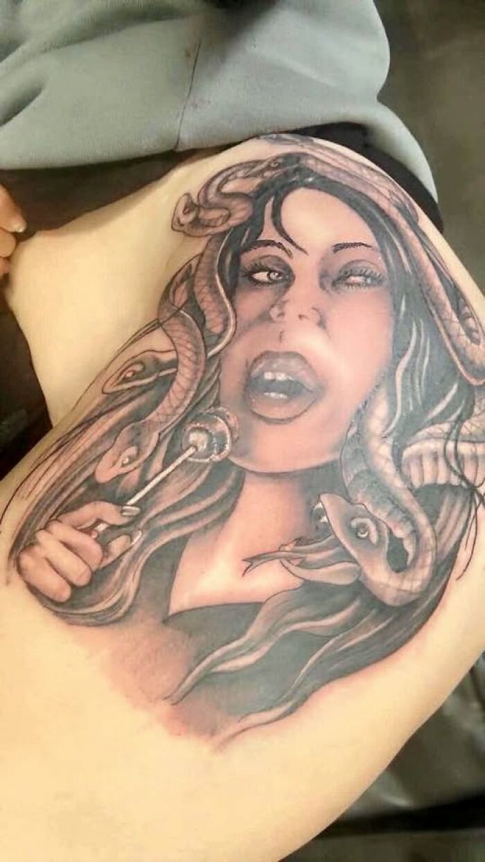 Tattoo of a woman with snakes for hair holding a lollipop, an example of people getting inked to look cool but with a permanent mistake.