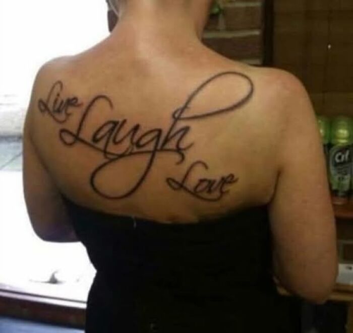 Tattoo of the phrase live laugh love on a person's upper back, an example of inked to look cool but a permanent mistake.
