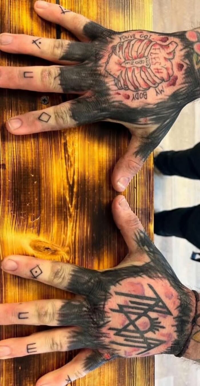 Hands covered in extensive tattoos including ribs and letters on fingers showing examples of inked mistakes.