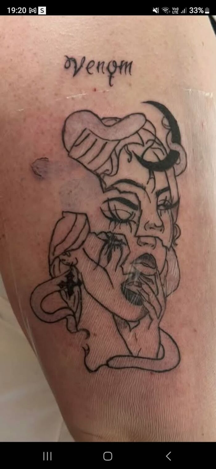 Black ink tattoo of a distorted female face and the word venom, showcasing a permanent tattoo mistake on skin.