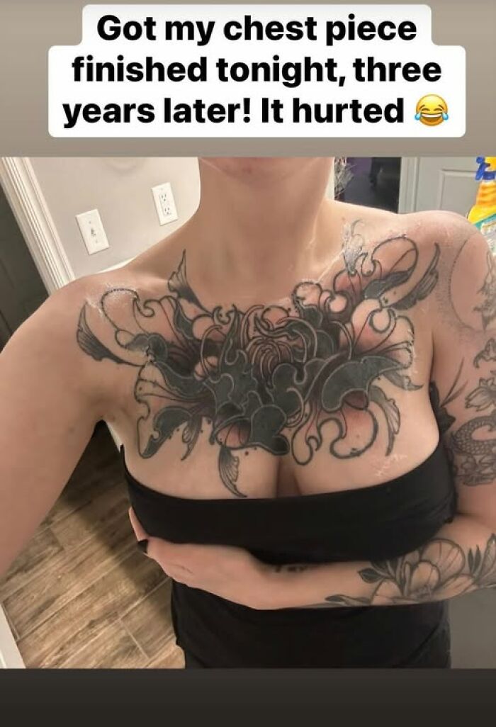 Woman showing a large chest tattoo with black ink, highlighting a cool tattoo design but a permanent mistake.