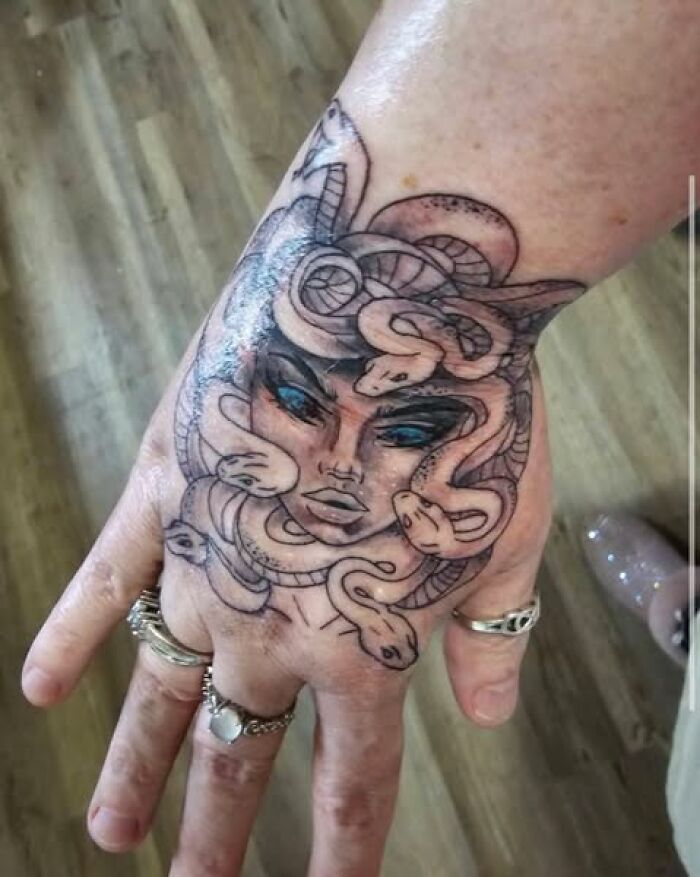 Tattoo of a Medusa face with snakes on a hand, showcasing a permanent mistake people got inked to look cool.