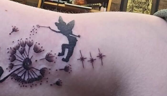 Tattoo of a fairy holding a dandelion with seeds and stars, an example of a permanent mistake in inked tattoos.