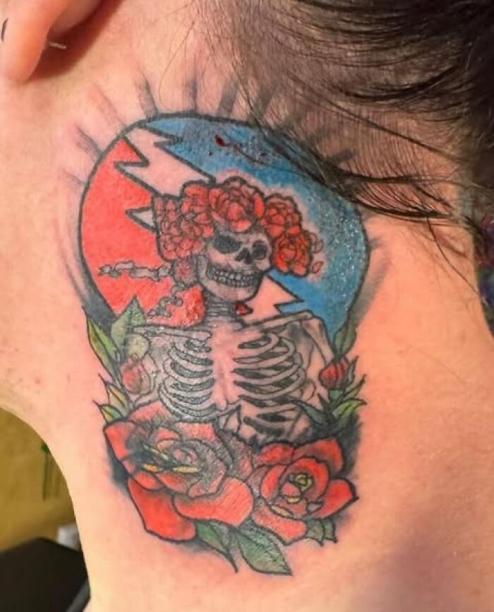 Colorful skeleton tattoo with roses and lightning bolt behind the ear, an example of people getting inked with a permanent mistake.