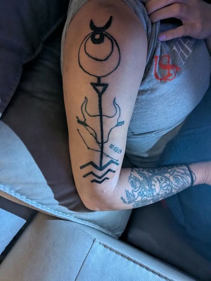 Tattoo on arm featuring abstract symbols and lines, an example of people getting inked to look cool but with a permanent mistake.