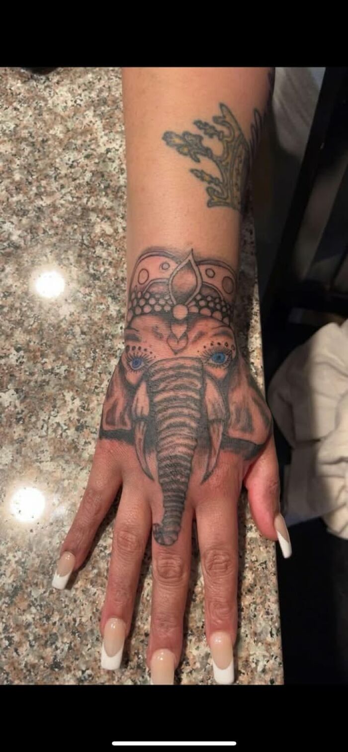 Elephant tattoo on hand with detailed blue eyes and decorative crown, an example of inked mistakes to look cool.