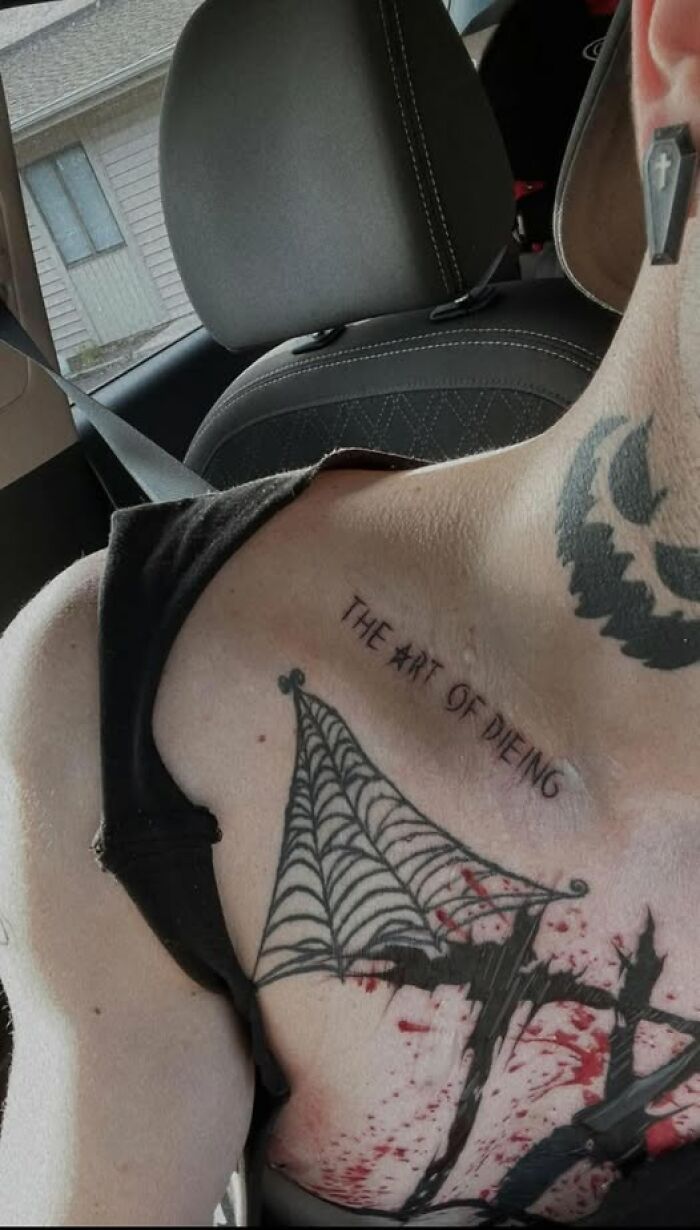 Tattoo with spelling mistake on chest showing the phrase the art of dieng in a car seat background.
