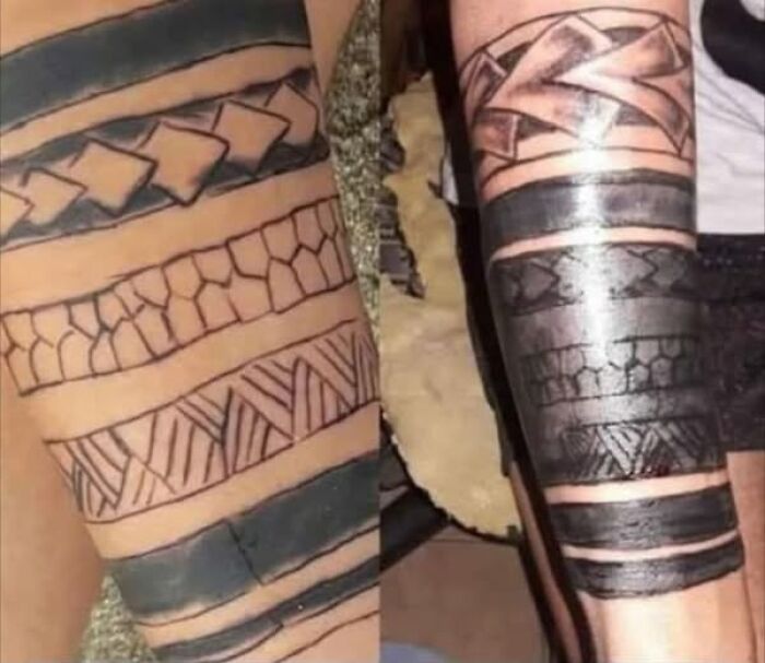 Close-up of two arms with bold tattoos showing permanent ink mistakes in tribal-style designs.