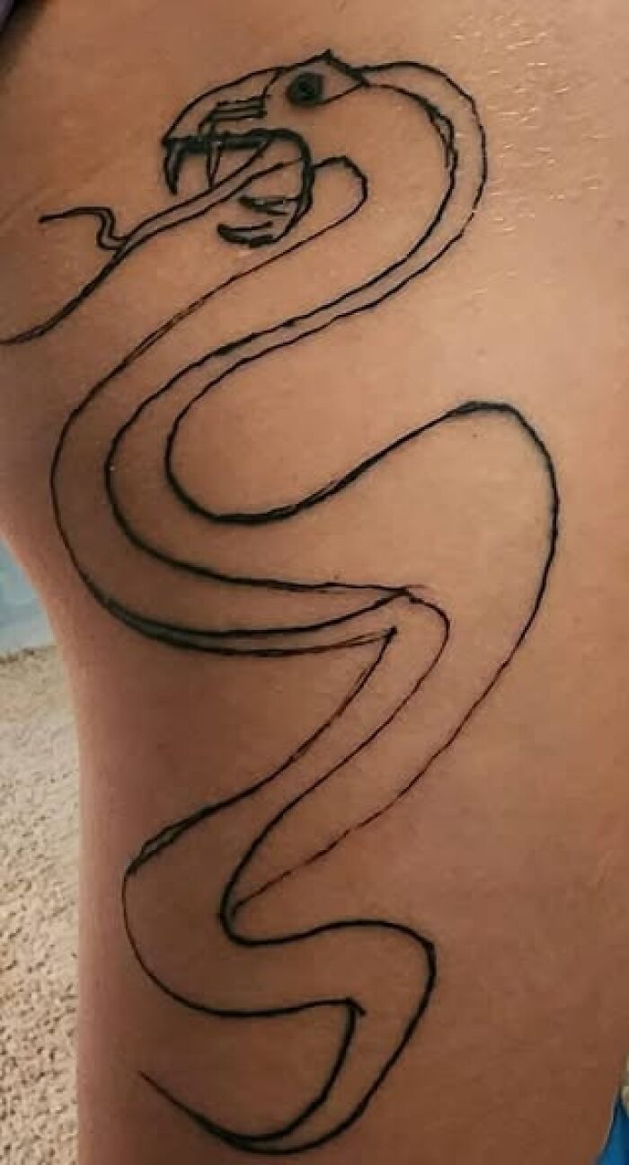 Outline tattoo of a snake with poorly drawn features, an example of people getting inked to look cool but with a permanent mistake.