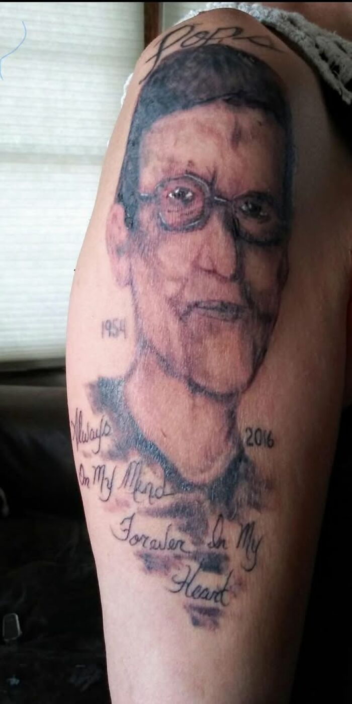 Tattoo of a portrait with glasses and handwritten text showing a permanent mistake in inked body art.