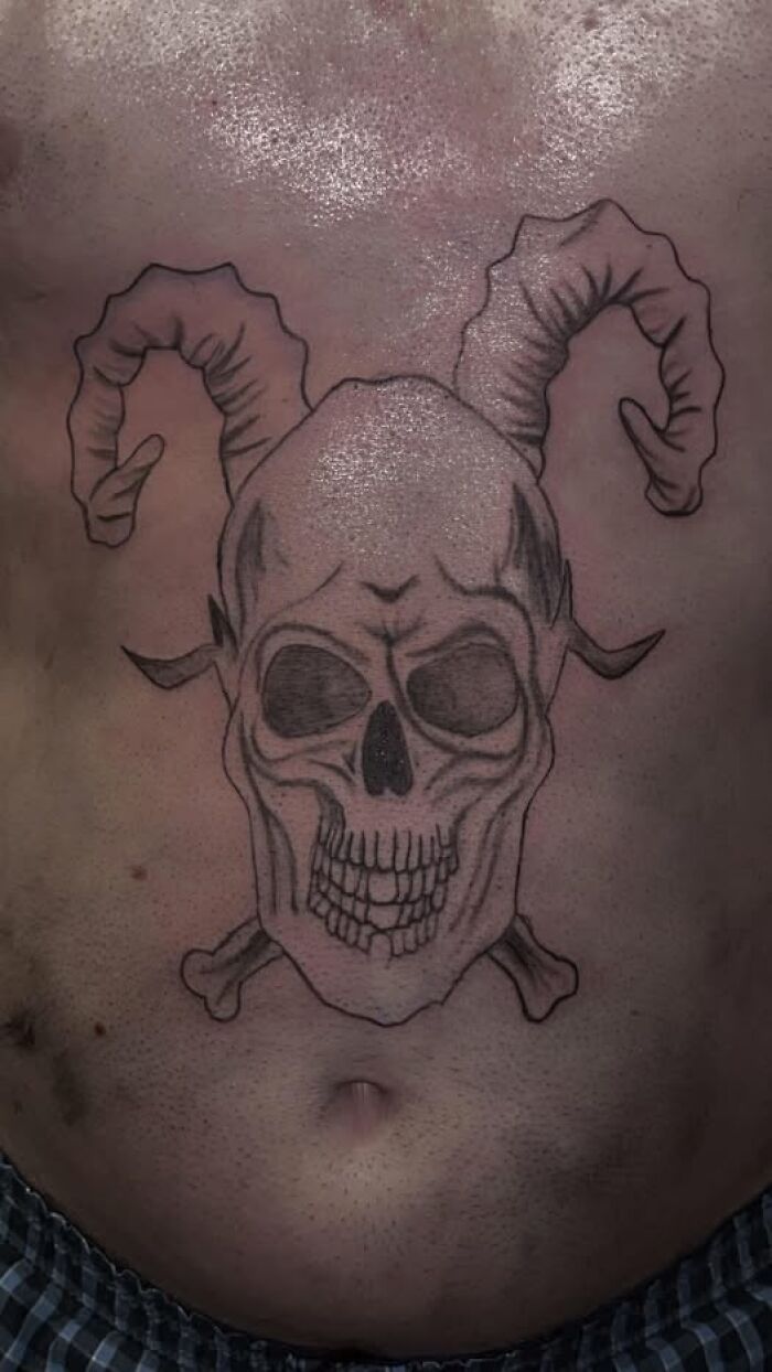 Tattoo of a skull with ram horns and crossbones on a person's torso from a collection of inked mistakes meant to look cool.