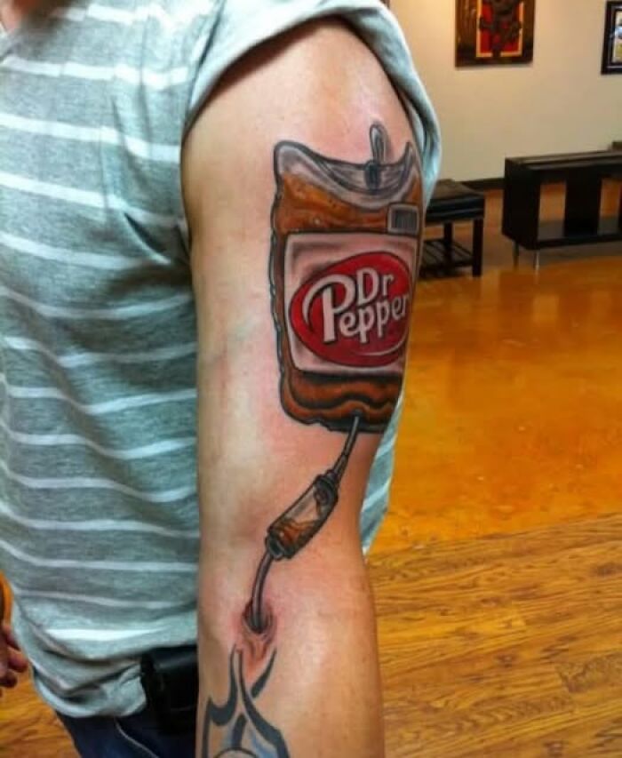 Arm tattoo of a Dr Pepper drink bag with a connected IV tube, showcasing a permanent ink mistake.