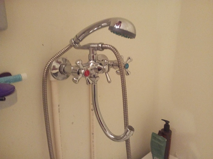 Shower faucet with poorly designed hose placement showing dumb interior design decisions.