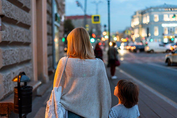 Woman and child walking on city street at dusk highlighting issue of guy refusing to watch kids during emergency. Woman and child walking on city street at dusk highlighting issue of guy refusing to watch kids during emergency.