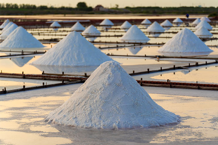 Salt piles drying in solar evaporation ponds, illustrating natural resource changes impacting humanity's future.
