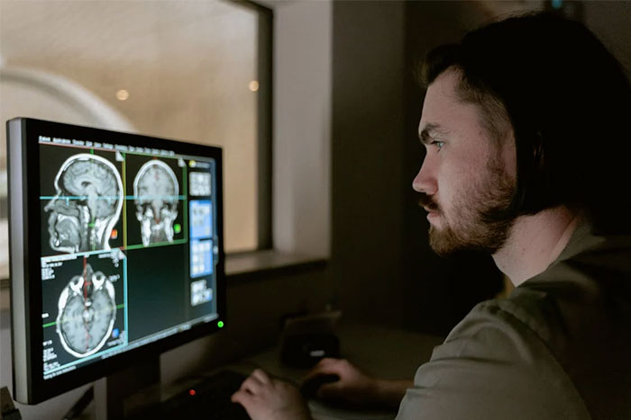 Man analyzing brain scans on computer screen, exploring future medical technology changing humanity in next 10-15 years