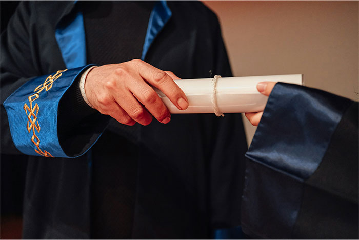 Person in academic robe handing a diploma to another person, symbolizing change impacting humanity in the next 10 to 15 years.