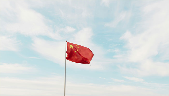 Red flag with yellow stars waving against a cloudy sky, symbolizing future changes impacting humanity.