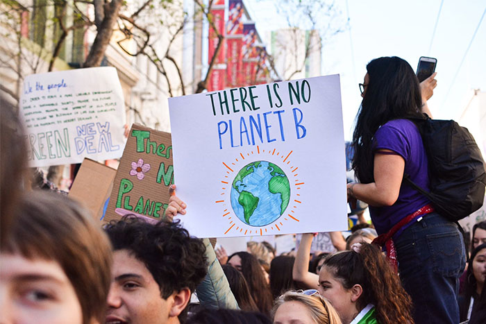 Crowd of young people holding environmental protest signs including no planet B, highlighting future changes impacting humanity.