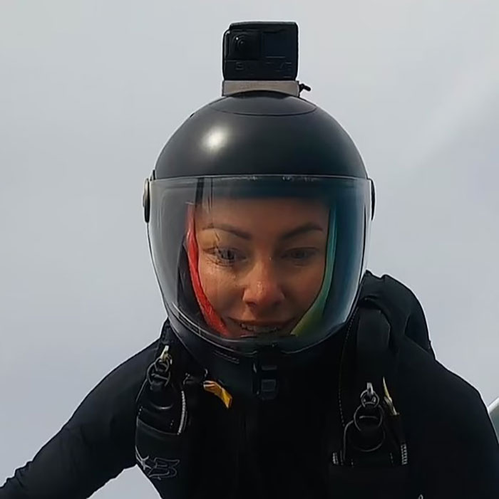 Experienced skydiver with over 400 flights wearing a helmet and gear, preparing for a jump in midair.