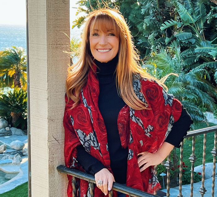Actress Jane Seymour posing outdoors in a red shawl, showcasing her youthful look and ageless beauty at 74 years old.