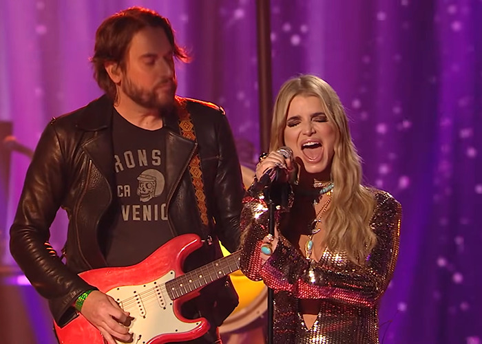 Jessica Simpson performing live on stage with guitarist, facing criticism and described as a train wreck by critics.