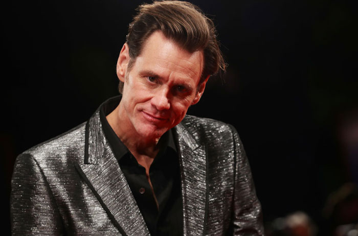 Jim Carrey wearing a shiny silver jacket, attending an event, with a focus on net worth and mansion drama.