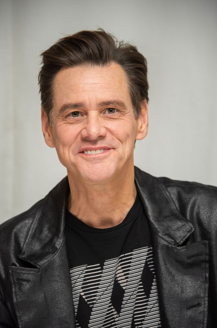 Jim Carrey smiling in a black patterned shirt and blazer, related to net worth and mansion drama news.