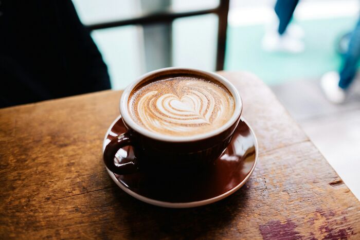 Cup of coffee with heart latte art on a wooden table, illustrating bartender stories beyond just pouring drinks.