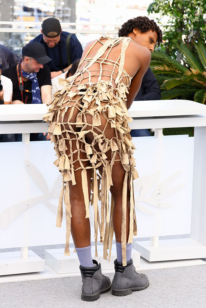 Model wearing a revealing netted dress with tassels at Cannes Film Festival, highlighting fashion disasters of 2025.