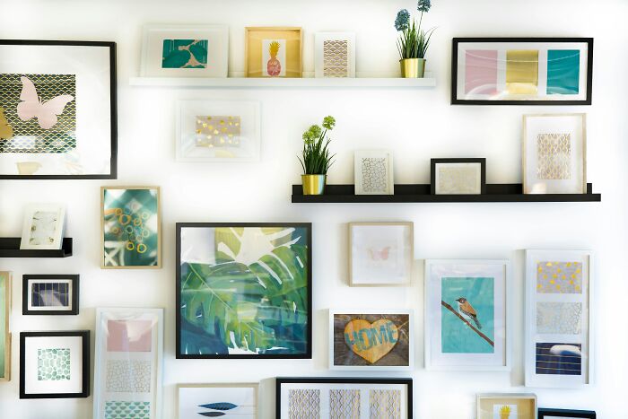 Wall decorated with framed art and plants, illustrating quirky and hilarious things girlfriends do secretly.