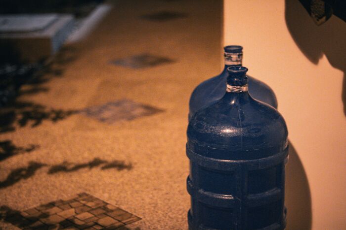 Two large blue water jugs placed on a tiled floor showing appalling facts people unaware of water storage.