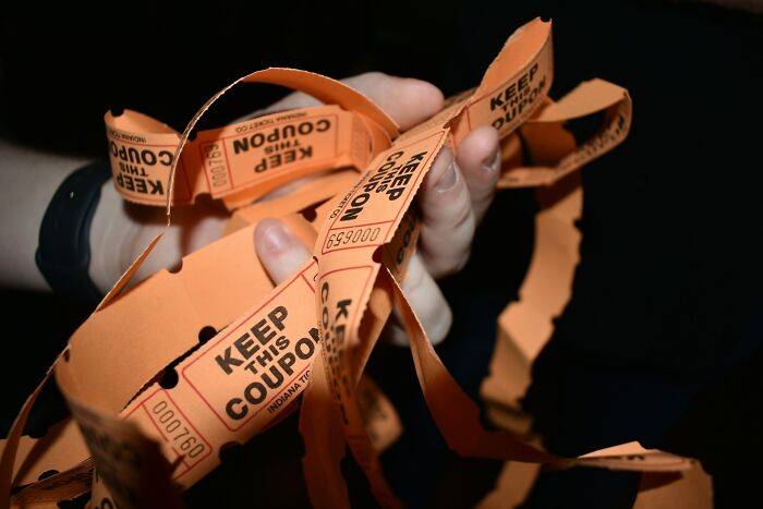 Hands holding multiple orange raffle tickets illustrating real-life cheat codes people swear by that work almost every time.