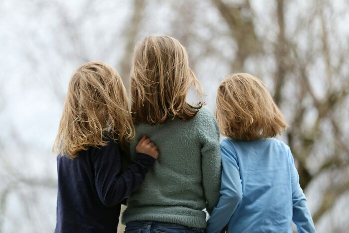 Three children with messy hair standing outdoors, illustrating hilariously bad names that make people question parenting choices.
