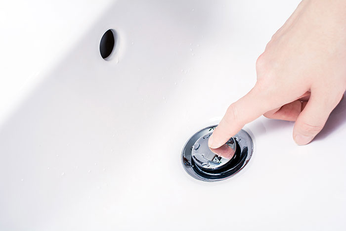 Person pressing bathtub drain stopper as a safety precaution shared online to help save lives and prevent accidents.