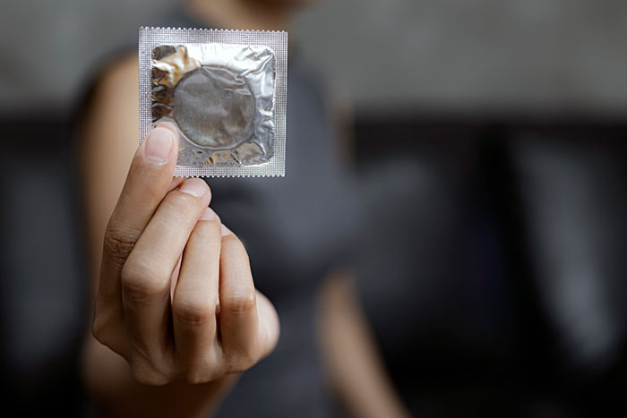 Person holding a c****m in foil packaging, illustrating one of the precautionary actions that saved lives shared online.