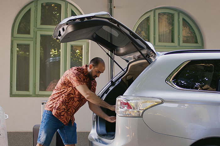 Man packing emergency supplies into car trunk as a precaution, illustrating things done that saved lives online shared by folks
