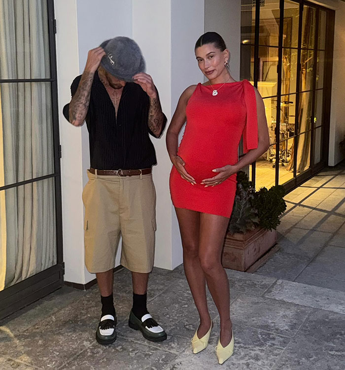 Justin Bieber and pregnant partner posing outdoors, linked to controversy over disrespect in Mother's Day post.