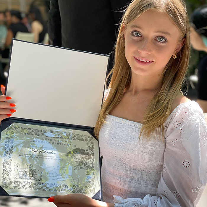 Teen girl holding graduation certificate, representing transgender courage and support in Liev Schreiber&rsquo;s family story.