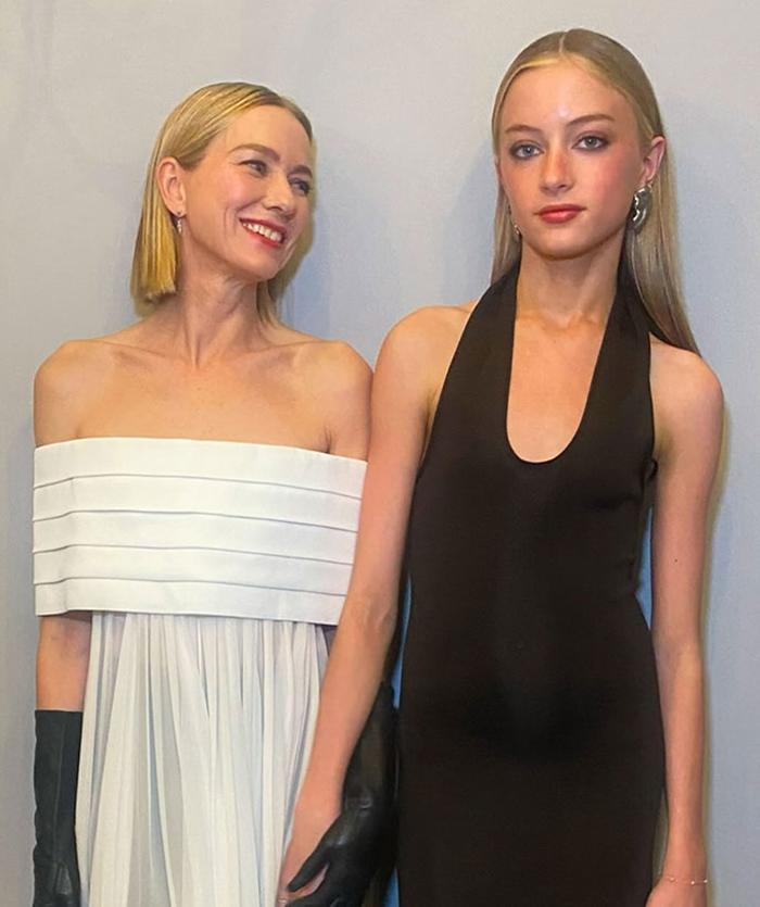 Woman in a white dress smiling at a young person in a black dress, relating to Liev Schreiber's teen daughter coming out as transgender.