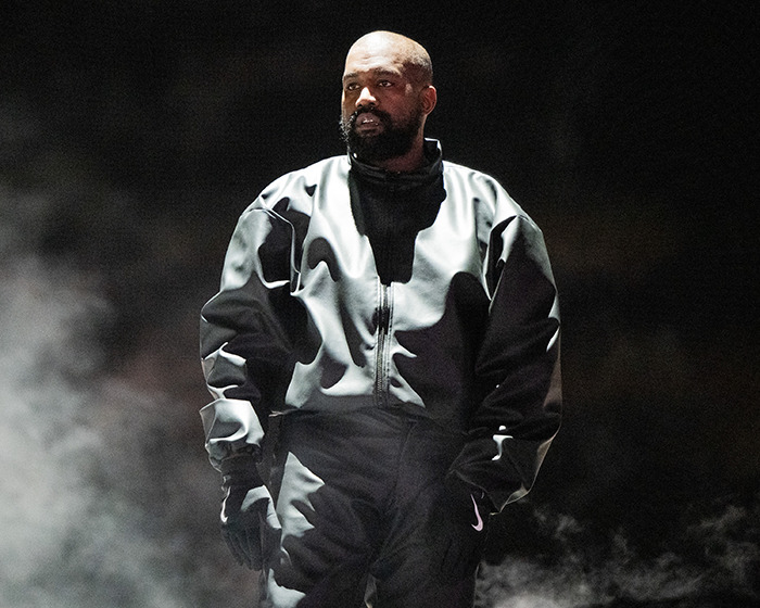 Kanye West wearing a dark outfit standing in smoky lighting, related to post about being subservient Bianca Censori master.