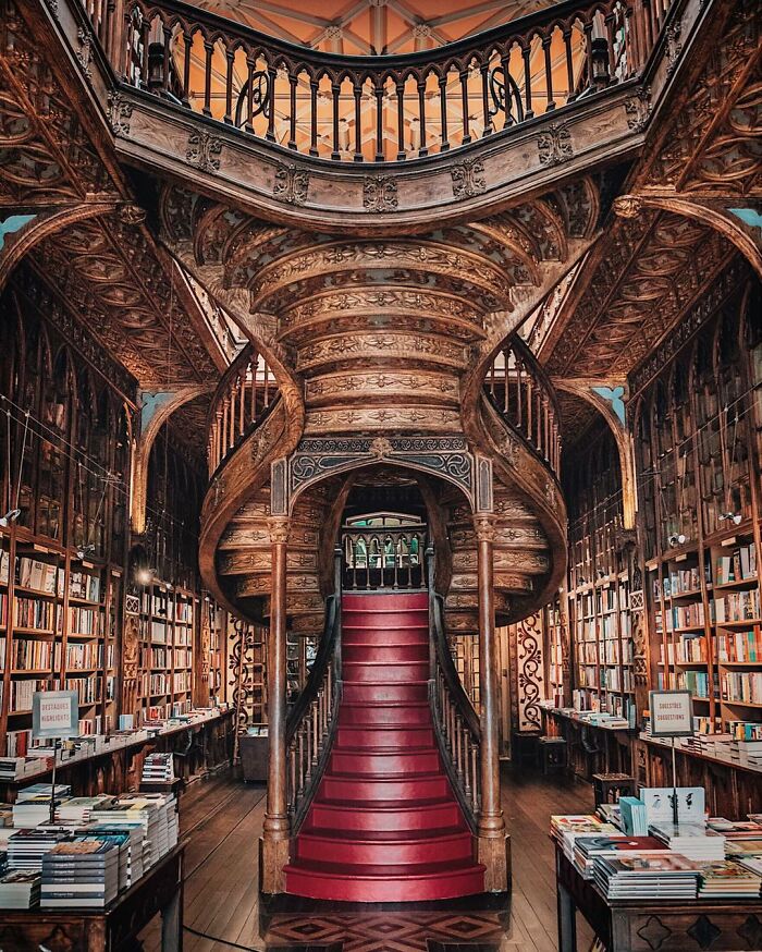 Ornate wooden staircase and shelves filled with books in a stunning and impressive bookstore interior design.