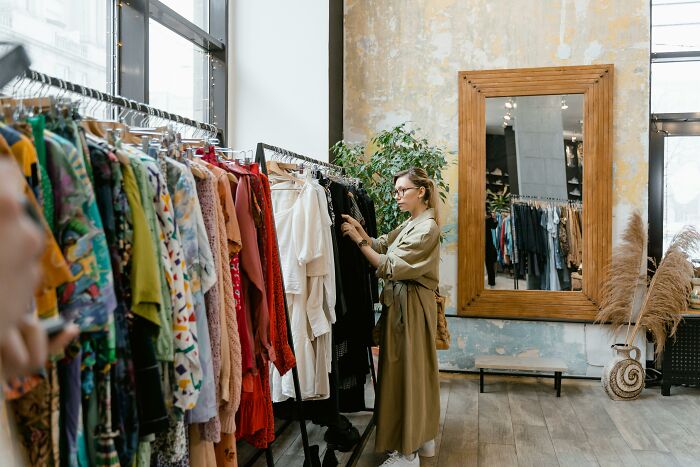 Woman browsing clothes in a boutique, representing themes of unhinged Karen and diabolical parent behavior in an intense setting.